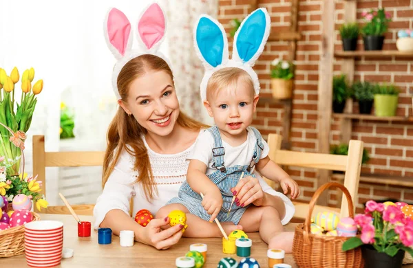 Happy easter! family mother and baby son paint eggs for holiday