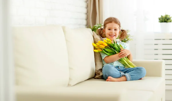 Gelukkig lachen kind meisje met gele tulpen thuis — Stockfoto
