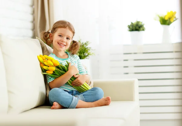 Gelukkig lachen kind meisje met gele tulpen thuis — Stockfoto