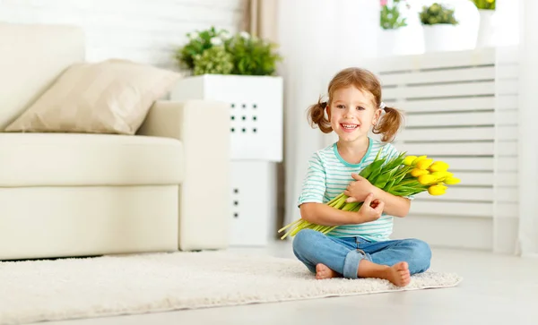 Happy laughing  child girl with  yellow tulips at home — Stock Photo, Image