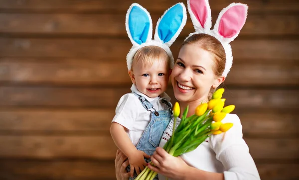 ¡Feliz Pascua! madre y bebé en orejas de conejo con flores amarillas — Foto de Stock