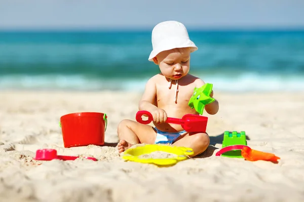 Bebé niño jugando con juguetes y arena en la playa — Foto de Stock