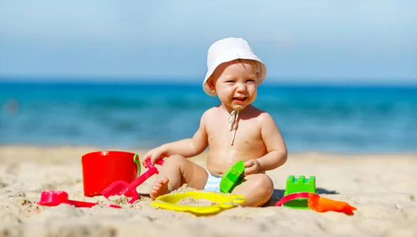 Bebé niño jugando con juguetes y arena en la playa —  Fotos de Stock