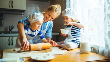 happy family in kitchen. mother and children preparing dough, ba