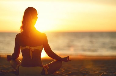 kadın yoga uygulamaları ve lotus pozisyonu Sahilde meditasyon