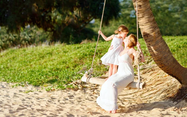 Familia feliz en la playa. madre sacudió niño en swing en summe —  Fotos de Stock