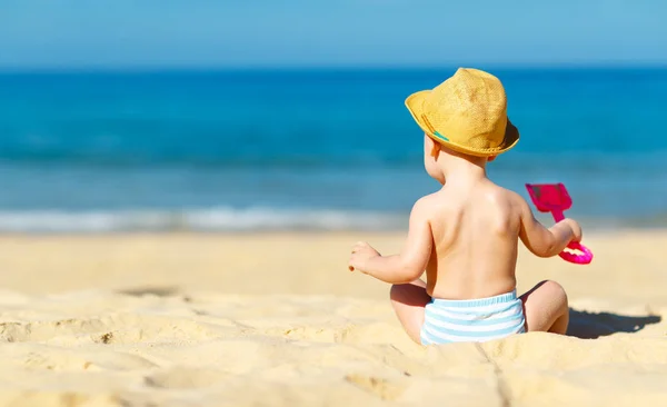 Хлопчик сидить назад з іграшками на пляжі — стокове фото
