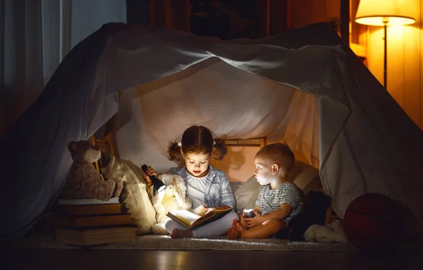 Kinderen jongen en meisje leesboek met zaklamp in de tent — Stockfoto