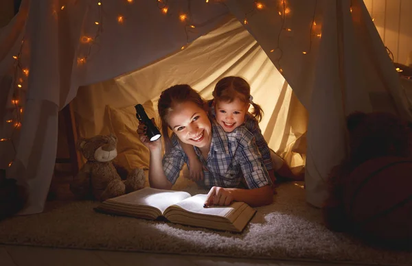 本と行く前に懐中電灯を持つ母と子の娘 — ストック写真
