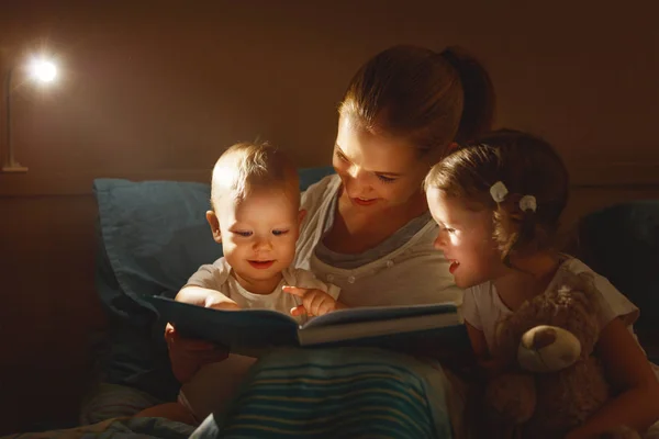 Madre lee a los niños libro en la cama — Foto de Stock