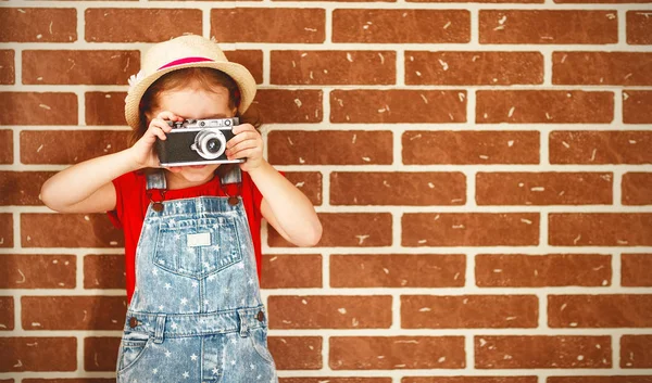 Joyeux enfant fille photographe avec caméra au mur de briques — Photo