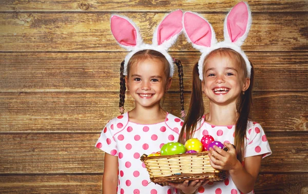 ¡Feliz Pascua! lindo gemelos niñas hermanas vestidas como conejos con e — Foto de Stock