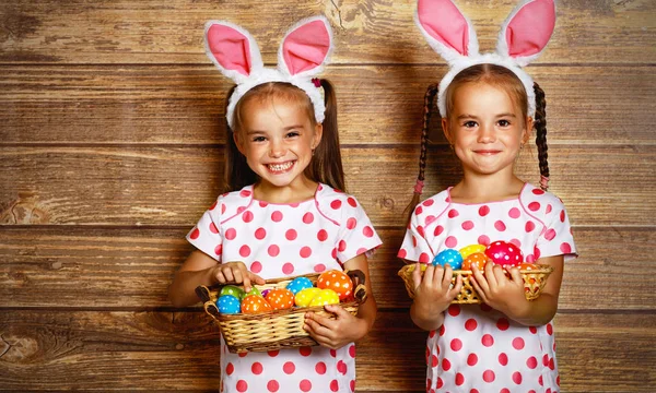 ¡Feliz Pascua! lindo gemelos niñas hermanas vestidas como conejos con e — Foto de Stock