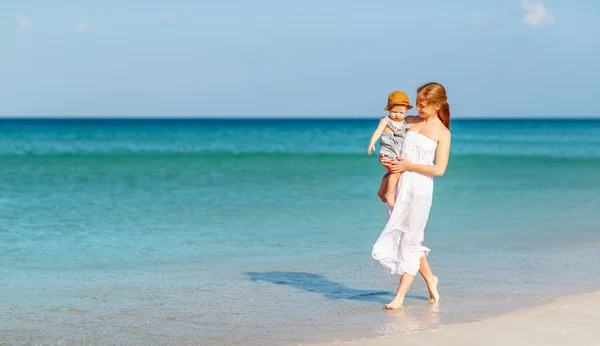 Happy family mother with baby son walks by ocean on beach in sum — Stock Photo, Image