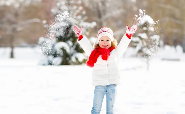 Счастливый ребенок бросает снег на зимнюю прогулку — стоковое фото