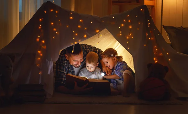 Lycklig familj far och barn en bok i tält på hom — Stockfoto