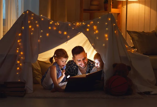 Glücklicher Familienvater und Kinder lesen im Zelt bei hom ein Buch — Stockfoto