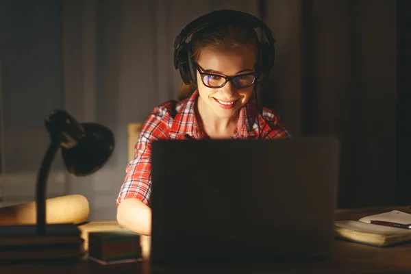 Jeune étudiante en écouteurs travaillant sur l'ordinateur à nig — Photo