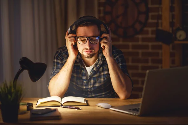 Man in headphones at computer home in evening in dark — Stock Photo, Image