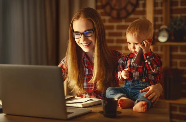 Kvinnan mor arbetar med en bebis hemma bakom en dator — Stockfoto