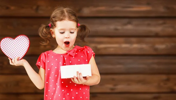 Glad skrattande barn girl med gåva Valentine's dag, trä — Stockfoto