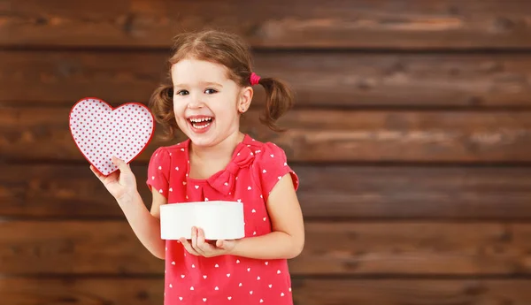 Happy laughing child girl with gift Valentine's Day, wooden — Stock Photo, Image