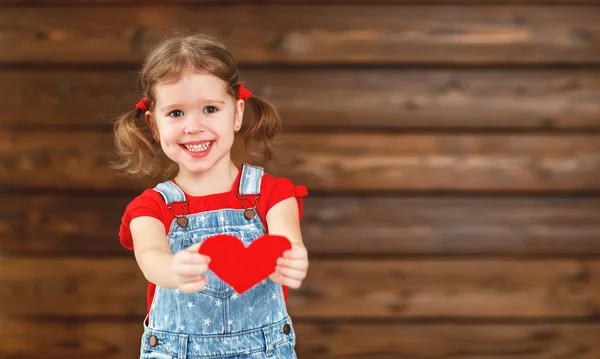 Happy laughing child girl with heart Valentine's Day, wooden — Stock Photo, Image