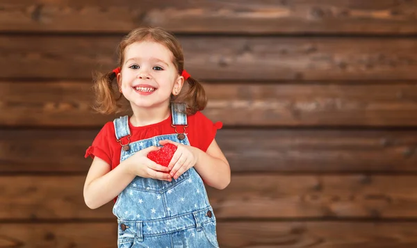 Happy laughing child girl with heart Valentine's Day, wooden — Stock Photo, Image