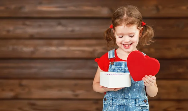 Счастливая смеющаяся девочка с подарком День Святого Валентина, деревянный — стоковое фото