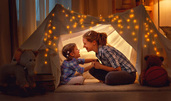 happy mother and daughter playing at home in tent