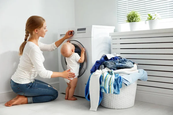 Mother housewife with baby engaged in laundry fold clothes into — Stock Photo, Image