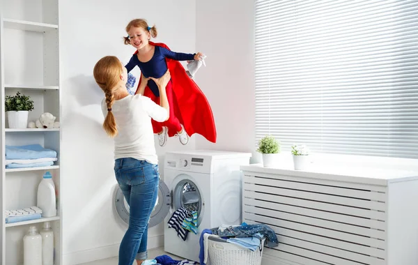 Familienmutter und Kind kleine Superhelden-Helferin in der Wäscherei — Stockfoto