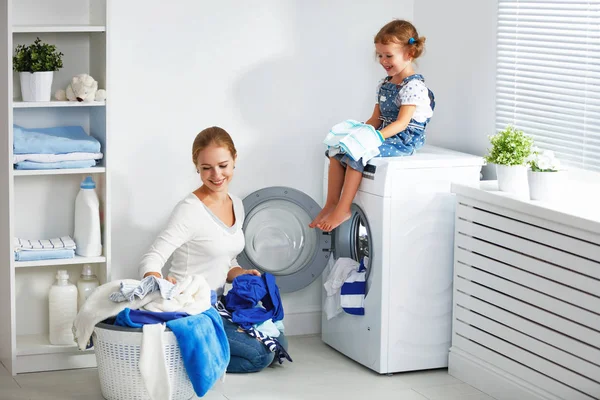 Семья мать и ребенок девочка в прачечной возле стиральной машинки — стоковое фото