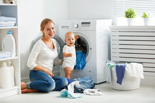Mother housewife with baby engaged in laundry fold clothes into — Stock Photo, Image