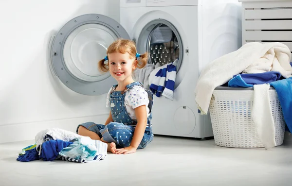 Child fun happy little girl to wash clothes in laundry room — Stock Photo, Image