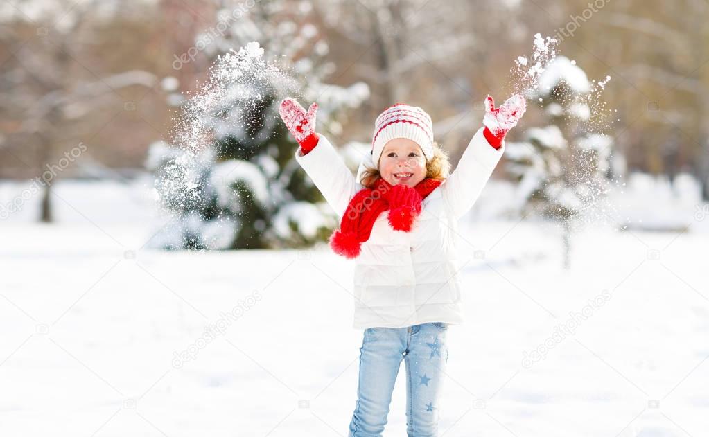 happy child throws up snow on a winter walk