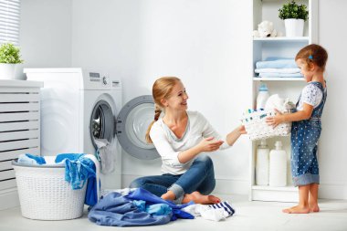 aile anne ve çocuk kız çamaşır odasında çamaşır makinesi ve kirli küçük yardımcısı giydirin