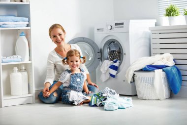 aile anne ve çocuk kız çamaşır odasında çamaşır makinesi ve kirli küçük yardımcısı giydirin