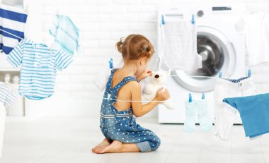 çocuk eğlence giyim ve oyuncak ayı içinde laundr yıkamak için küçük kız