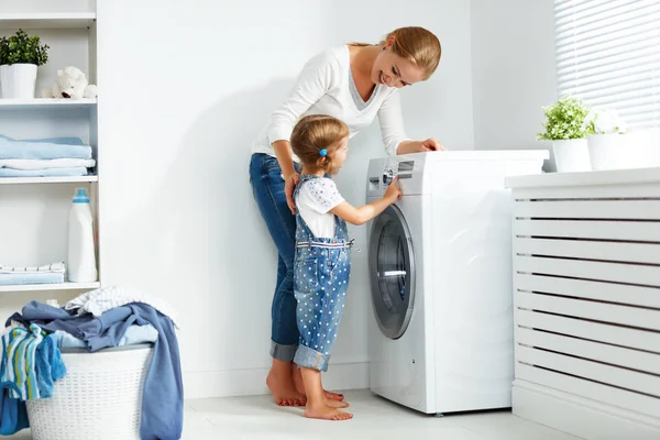 Mère de famille et enfant fille dans la buanderie près de machine à laver — Photo