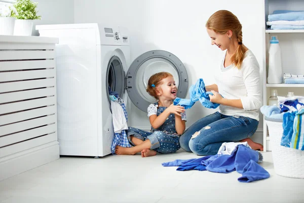 Семья мать и ребенок девочка в прачечной возле стиральной машинки — стоковое фото