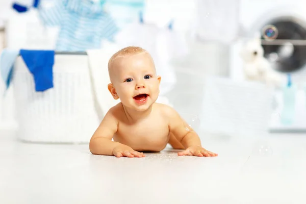 Fun happy baby boy to wash clothes and laughs in laundry — Stock Photo, Image
