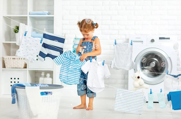 Niño divertido feliz niña para lavar la ropa en la sala de lavandería —  Fotos de Stock