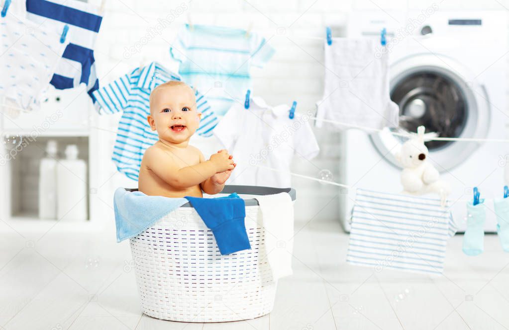 fun happy baby boy to wash clothes and laughs in laundry