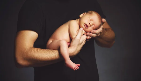 Bebê recém-nascido nas mãos de seu pai no escuro — Fotografia de Stock