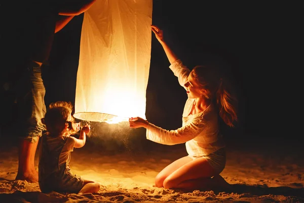 Família enviar ar celestial lanterna lâmpada em voo na praia — Fotografia de Stock