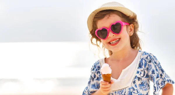 Menina feliz comendo sorvete na praia — Fotografia de Stock