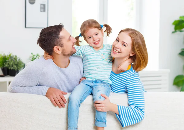 Família feliz rindo e abraçando em casa no sofá — Fotografia de Stock