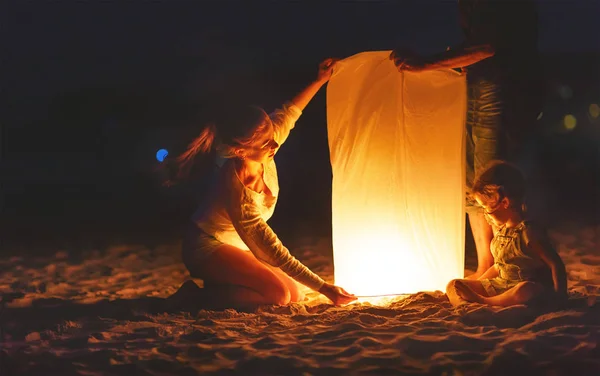 Família enviar ar celestial lanterna lâmpada em voo na praia — Fotografia de Stock