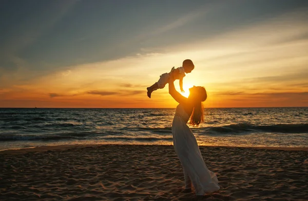 Feliz familia madre con bebé hijo camina por el océano en la playa en suma —  Fotos de Stock
